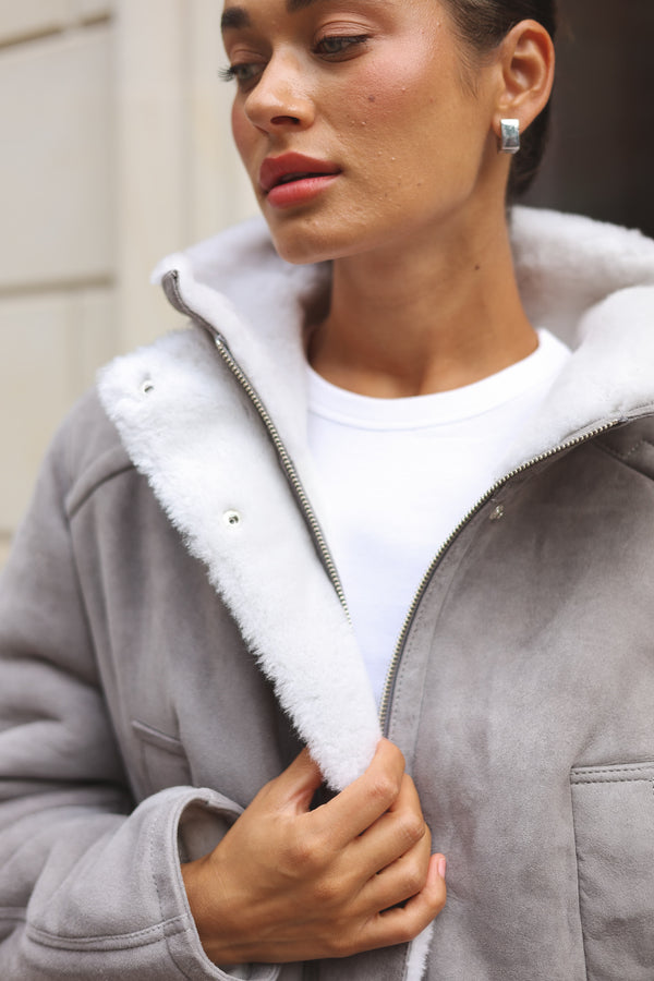 Grey merino sheepskin jacket with soft white lining and cropped silhouette, perfect for winter.